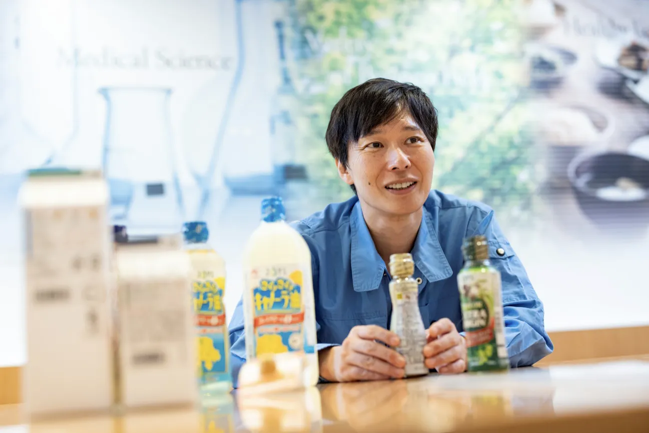 さまざまな種類があるJ-オイルミルズの家庭用食用油の容器を手に取る滝沢さん。