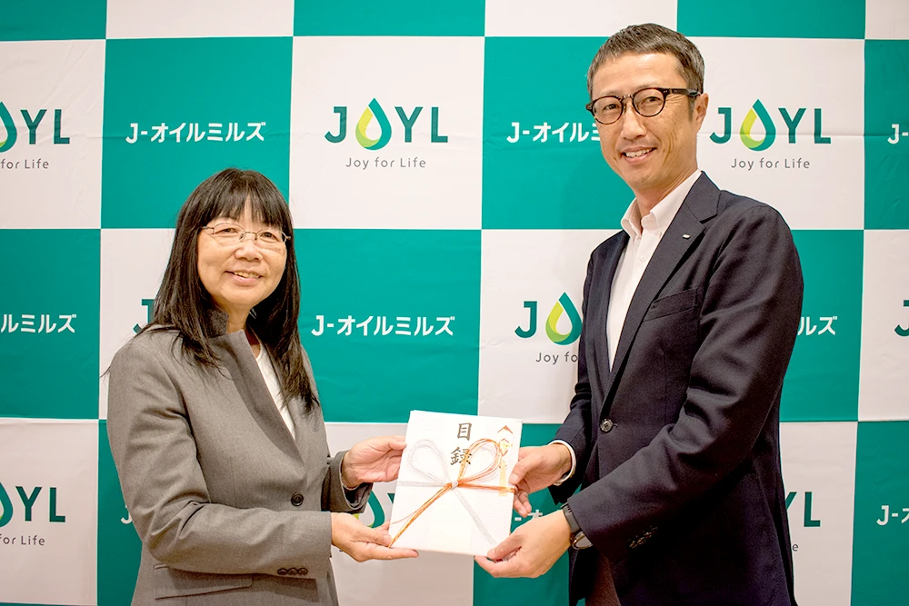 JEAN 理事 吉野美子氏（左）、当社執行役員 マーケティング統括部長 佐藤 亮（右）＝10月23日、寄付金の贈呈式を開催